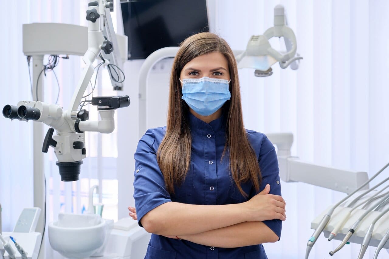 Portrait of young female doctor dentist in medical face mask in dental office